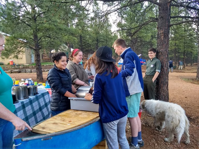 Small group of campers CIT and staff, washing dishes and chatting happily around the "dish canoe"