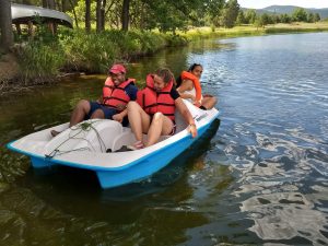 Counselor and two campers in the paddle boat, all in lifejackets