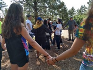 Group of campers and staff holding hands in two concentric circles
