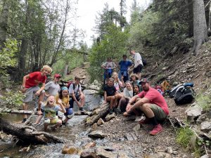 group of campers and staff posing in and around a small mountain creek